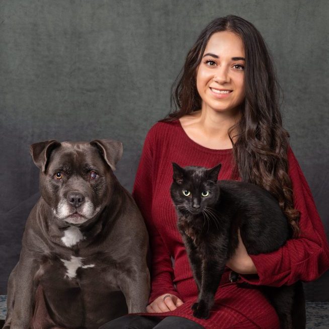 http://A%20dark%20haired%20young%20female%20holding%20a%20black%20cat%20with%20a%20senior%20dog%20sitting%20next%20to%20her