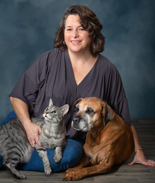 http://Woman%20with%20brown%20shoulder%20length%20sitting%20with%20dog%20and%20cat